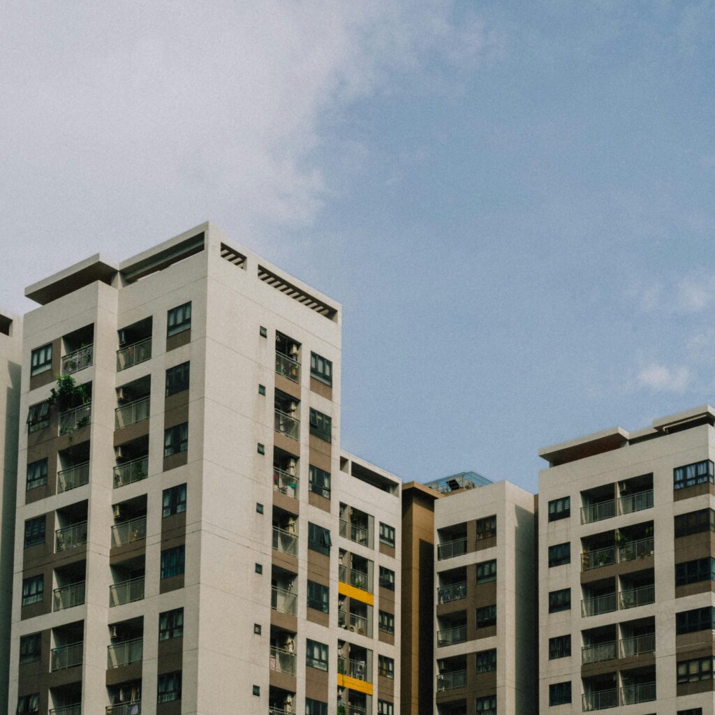 High-rise apartment buildings with balconies under a bright blue sky, showcasing urban architecture.